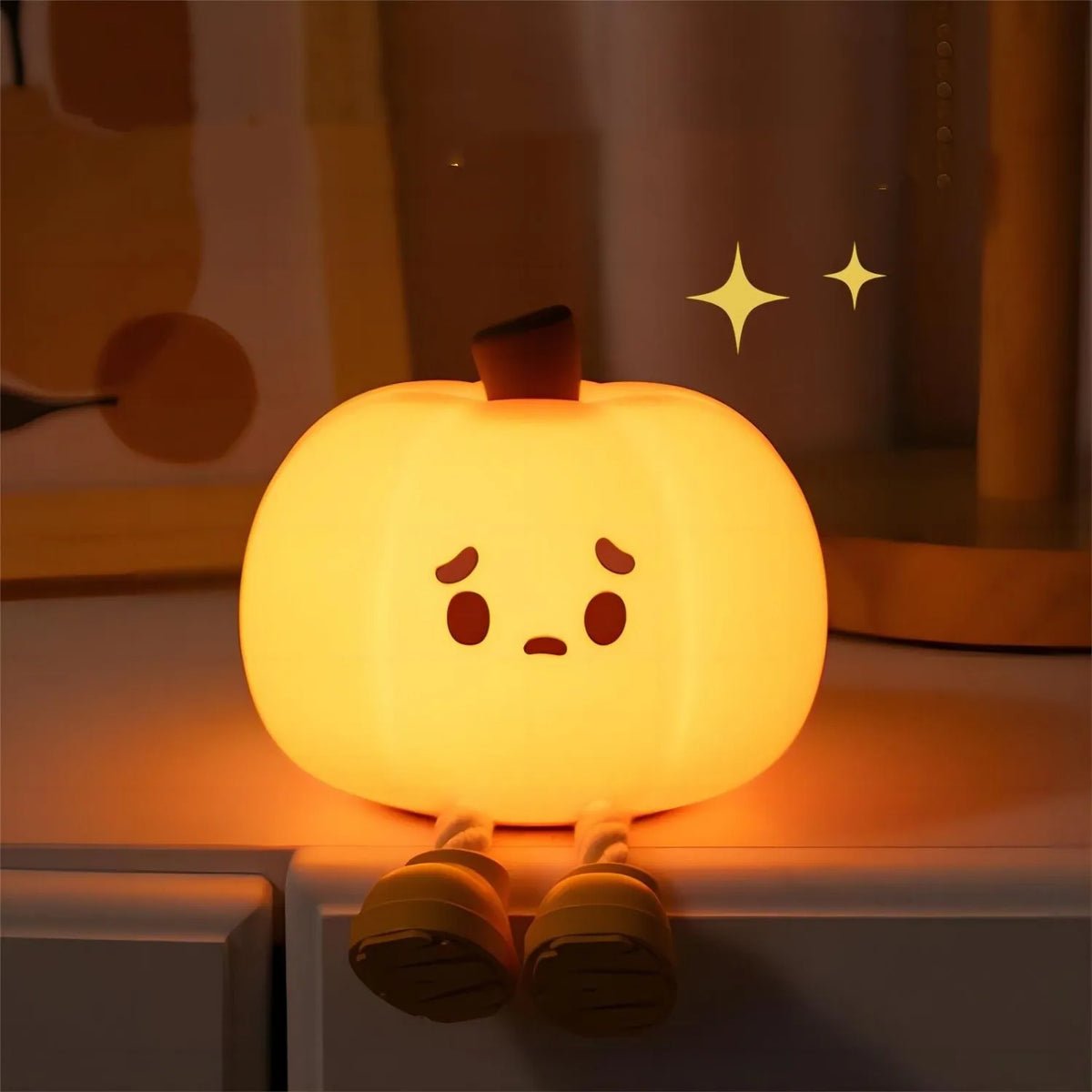 The silicone pumpkin night light glowing on a bedside table